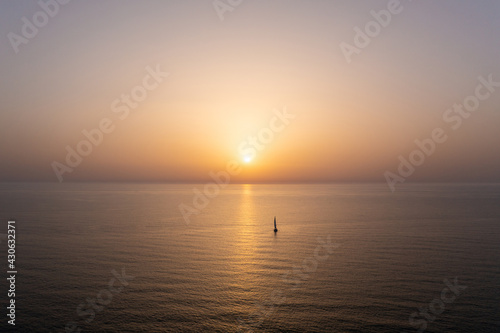 Sail boat sailing slowly towards a setting Sun in the Mediterranean Sea. © STOCKSTUDIO