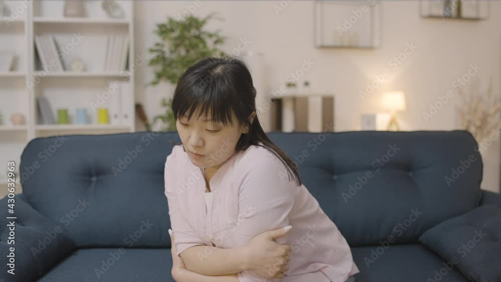 Pensive asian woman sitting on couch alone, suffering depression over troubles Pensive asian woman sitting on couch alone, suffering depression over troubles