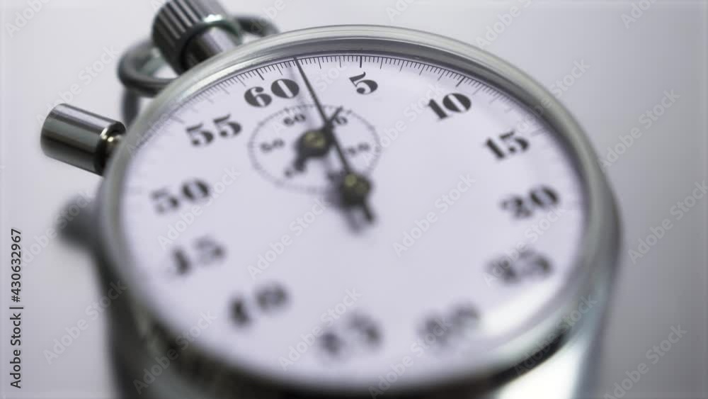 Macro shot of a classic metallic retro mechanical analog stopwatch against a silver background, counting down the seconds. Time management concept. Macro shot of a classic metallic retro mechanical analog stopwatch against a silver background, counting down the seconds. Time management concept.