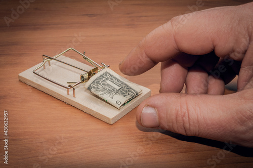 Man try to steal a one dollar bill banknote from a mouse trap photo