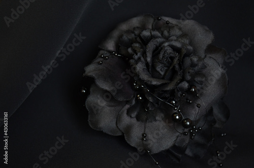 black flower brooch on black background. Decoration, hair clip