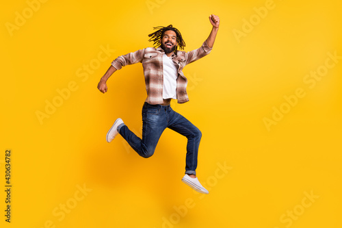 Full length body size photo of cheerful jumping man gesturing like winner isolated on bright yellow color background