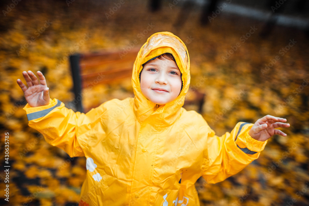 Child in the yellow raincoat walks in the forest and has fun Child in the yellow raincoat walks in the forest and has fun