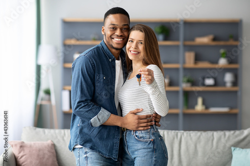Slika na platnu Happy young multiracial couple holding home keys and hugging