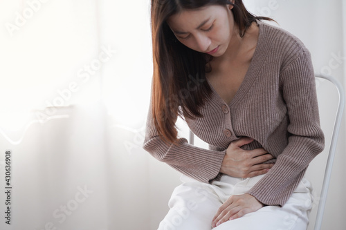 Obraz na płótnie Young Asian woman feel sick and suffering from strong abdominal pain stomachache