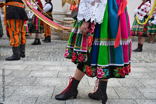 People dressed in polish national folk costumes from Lowicz region during annual Corpus Christi procession. Close up of traditional colorful striped folk dress, shoes and embroidery