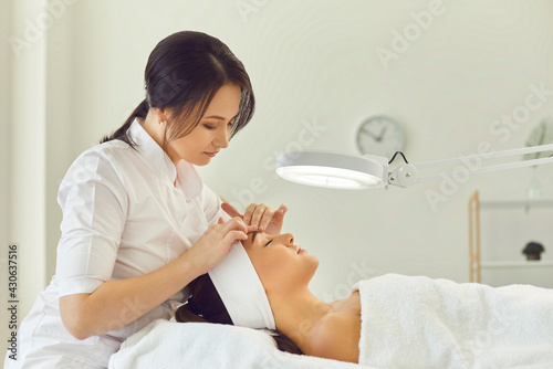 Woman dermatologist touching womans forehead during skin examination