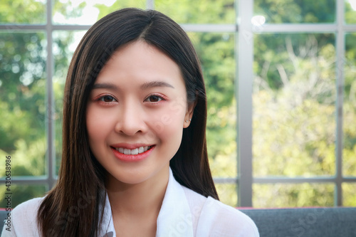 Woman beautiful white skin long hair asian Have a beautiful smile, look healthy. Sit on the sofa in the living room at home. The concept of health care for women in their 30s.