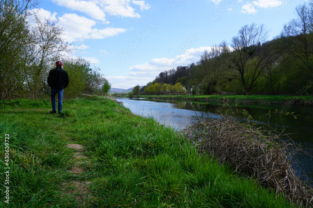 Obraz premium ein radfahrer macht pause und läuft an dem Fluss Leine entlang - a cyclist takes a break and walks along the river Leine