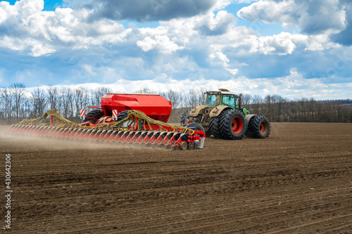 Fototapeta sowing work in the field in spring. Tractor with seeder