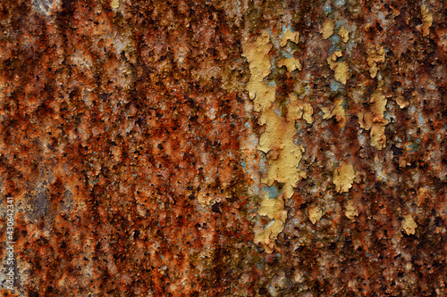 Shallow depth of field photo of rusty painted metallic texture, old iron with shabby cracked paint and scratches. Abstract metal background, wallpaper, template. Brown, yellow colors.