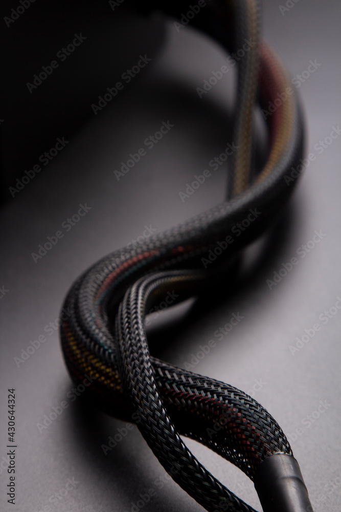 Cable snake skin. Black braided wires in bundle on black background. Braided Sleeving. Data line protection. Wire Flame-retardant nylon tube Cable snake skin. Black braided wires in bundle on black background. Braided Sleeving. Data line protection. Wire Flame-retardant nylon tube