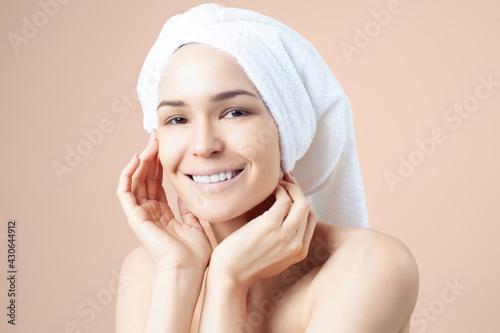Cute positive girl in towel on her hair on beige background