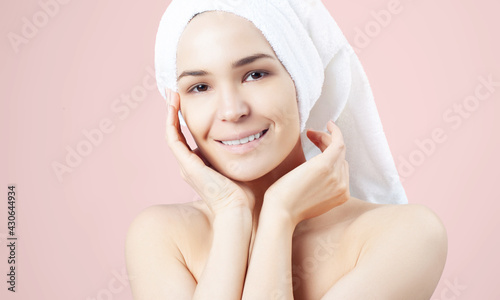 Cute positive girl in towel on her hair on pink background