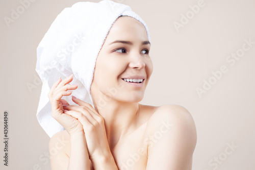 Cute positive girl in towel on her hair on beige background