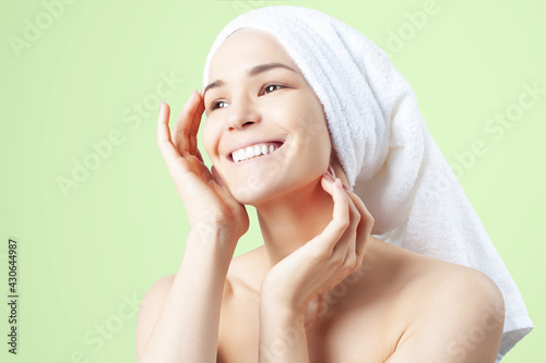 Cute positive girl in towel on her hair on green background