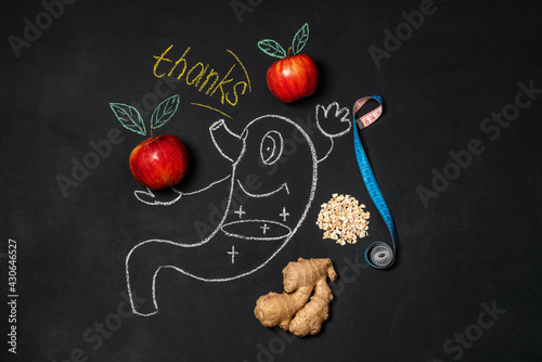 Good digestion concept. A funny stomach drawn on a chalk board next to apples and gingerbread. Place for text