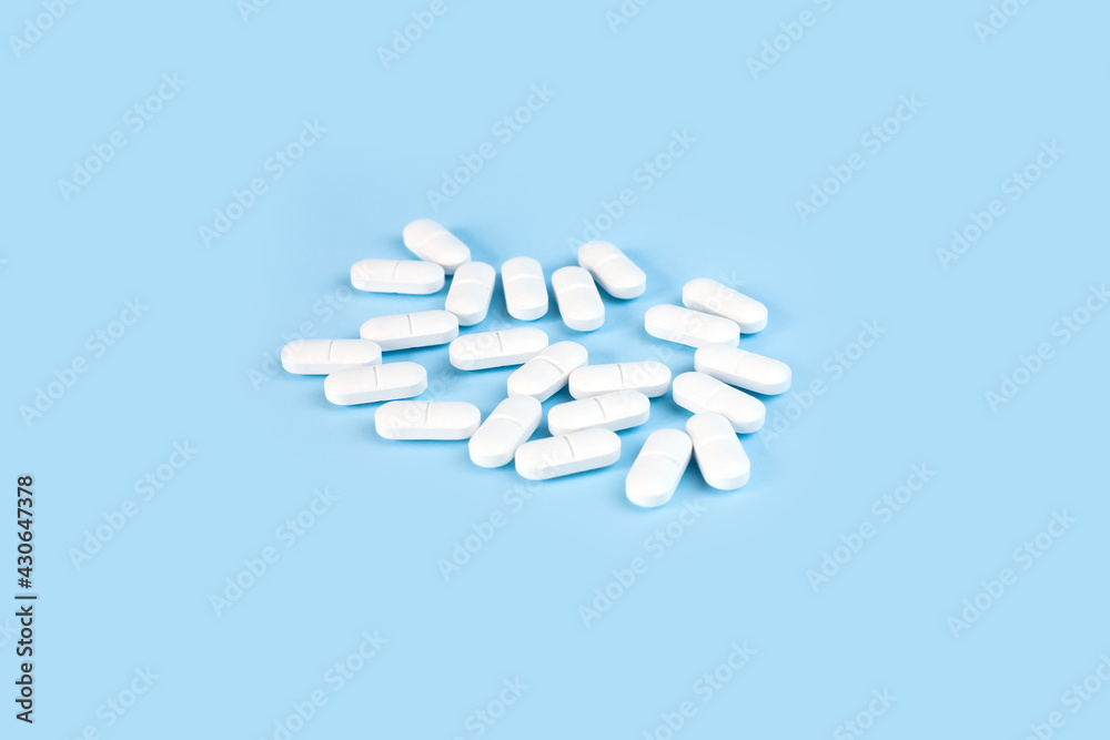 White pills on the blue background. Healthcare and medicine. Copy space. Close-up.