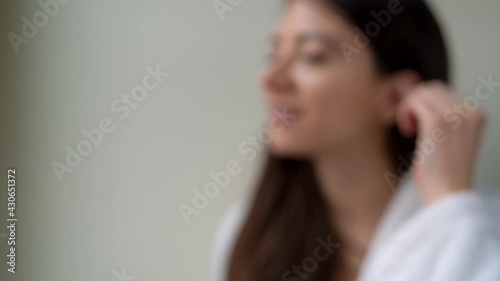 Young woman is holding in hand disposable cotton bud, swab, stick. Girl is cleaning, washing her auricle. Personal hygiene and care product concept. Prevention of ear diseases. Earwax removal. photo