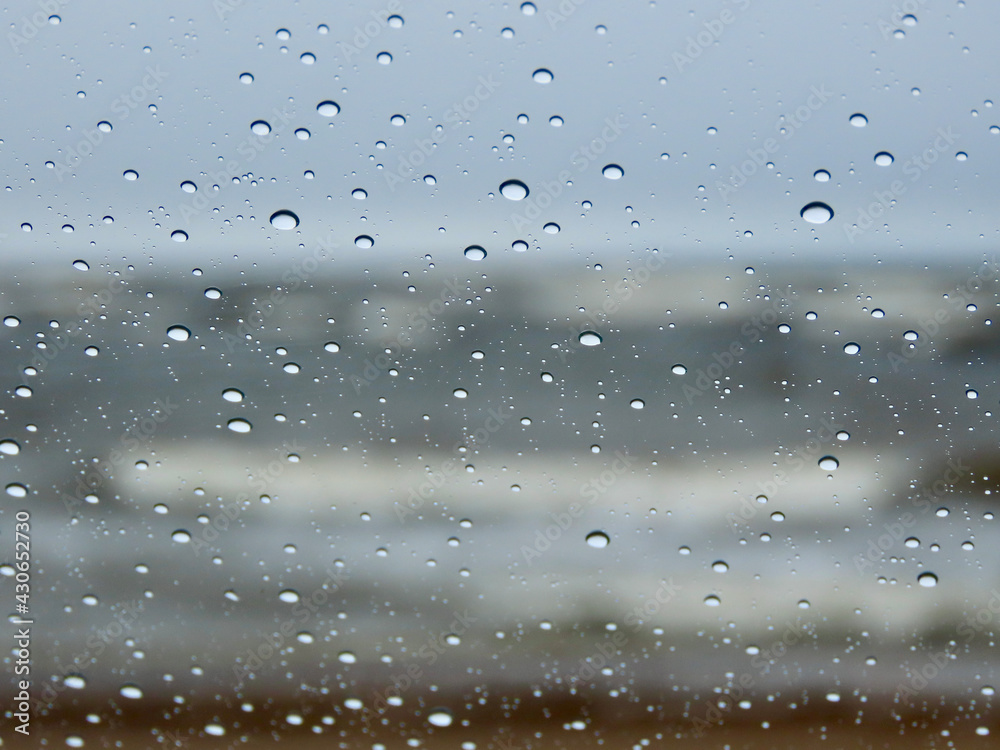 Baltic sea waves during a spring storm seen through a window with raindrops close up and bokeh blurry grey blue sea, huge white waves in far background Baltic sea waves during a spring storm seen through a window with raindrops close up and bokeh blurry grey blue sea, huge white waves in far background