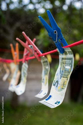 Money laundering. Money (EURO) banknotes hanging on a laundry line attached with colorful clips
