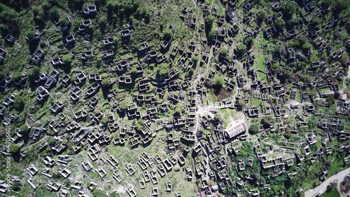 Drone view on world famous Kayakoy ghost town near to Olludeniz, Fethiye. The old ancient city on the beautiful green slope of the hill.
