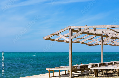 Sun loungers and a wooden shed on the old pier by the sea. Bright blue sky and calm sea, sea view vacation. The beginning of the summer season on the Black Sea coast © Ed