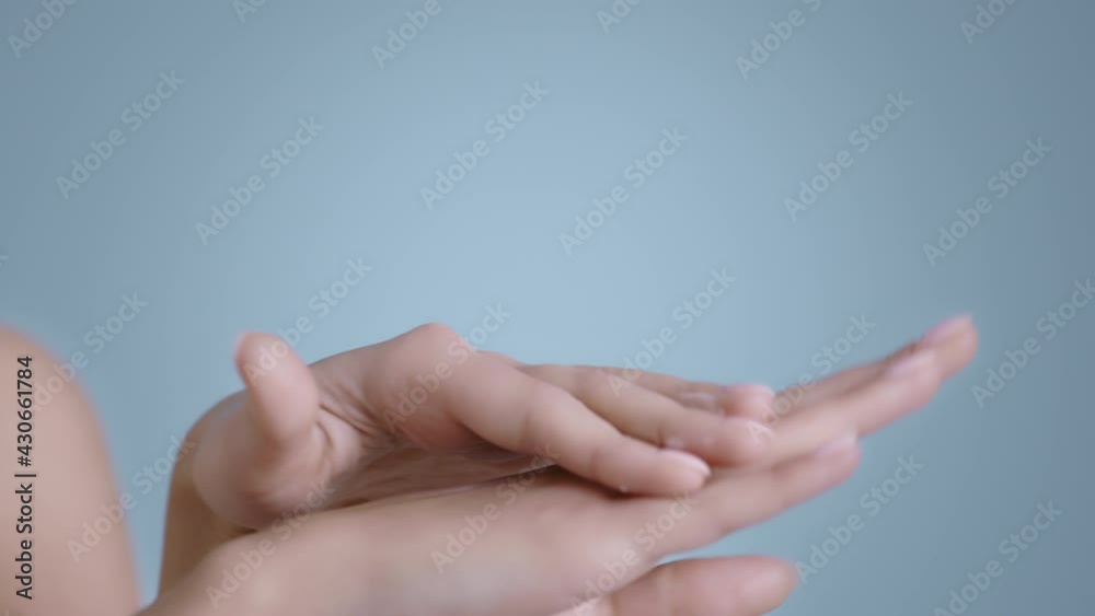 Close up view of female person with nude finger nails color putting and massaging cream on hands. Close up view of female person with nude finger nails color putting and massaging cream on hands.