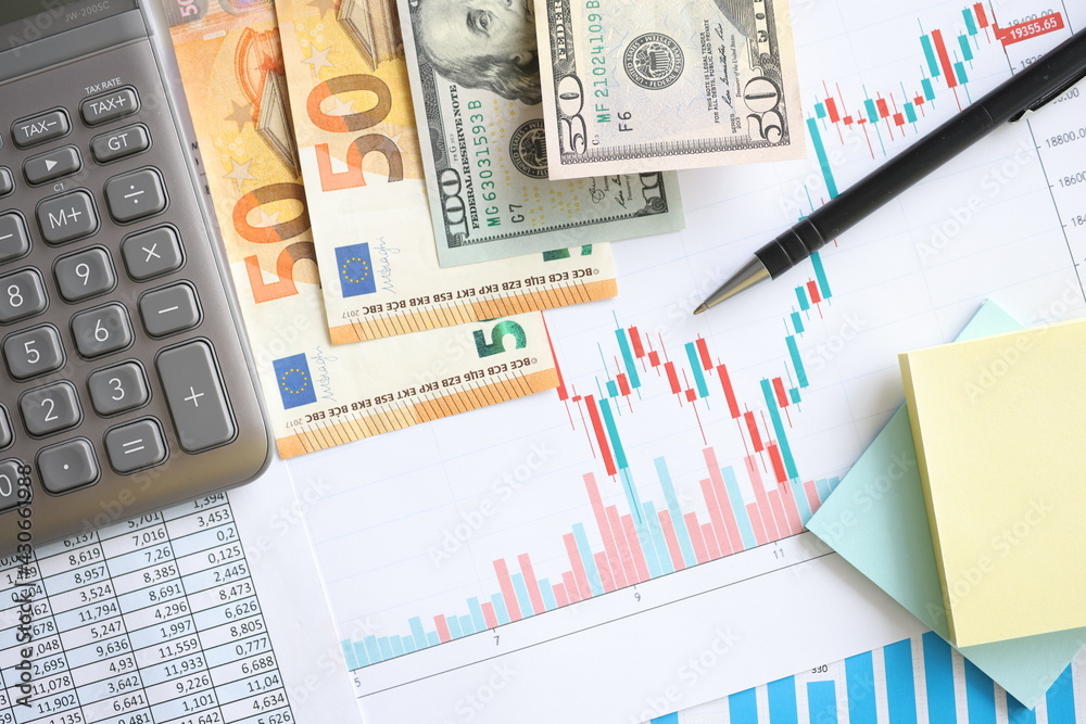 Money and calculator lying on documents with chart closeup Money and calculator lying on documents with chart closeup
