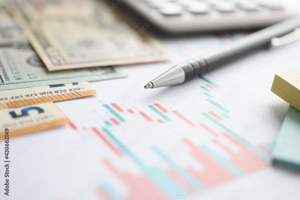 Money and ballpoint pen lying on documents with charts closeup Money and ballpoint pen lying on documents with charts closeup