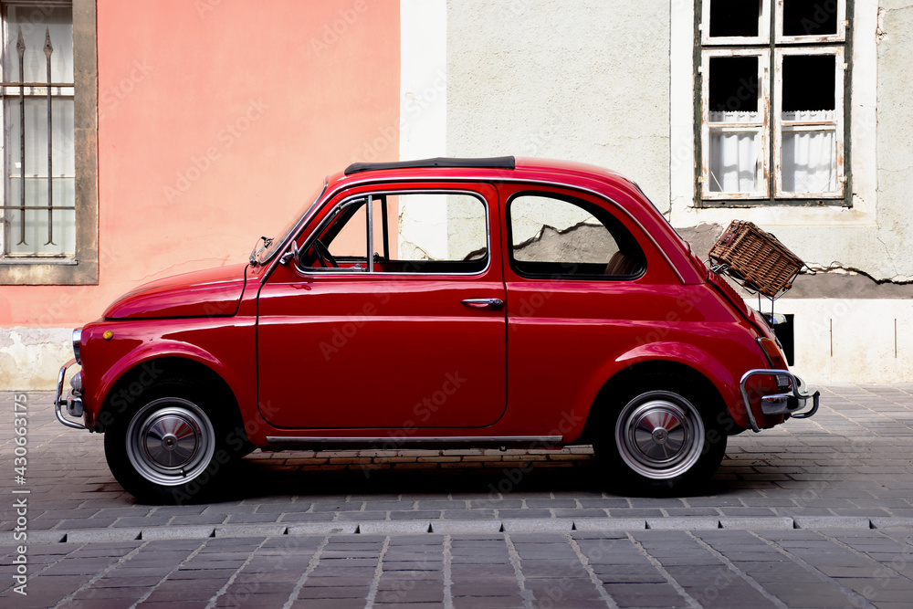 red stylish vintage FIAT 500 small car in side view in front of grunge  stucco facade of old house. weaved picnic basket or box attached to the  rear. editorial photo. transportation. Photos