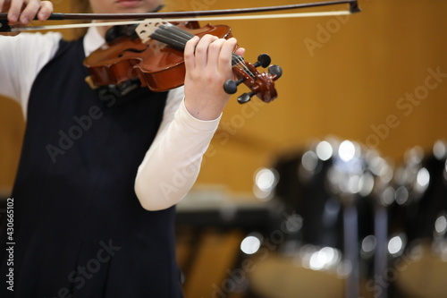 A girl student plays a musical instrument on the violin with a bow at a school concert.Close-up photo.Selective Focus