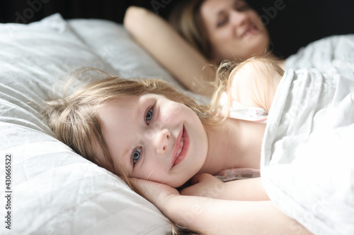 Little beautiful girl lying in bed with mom