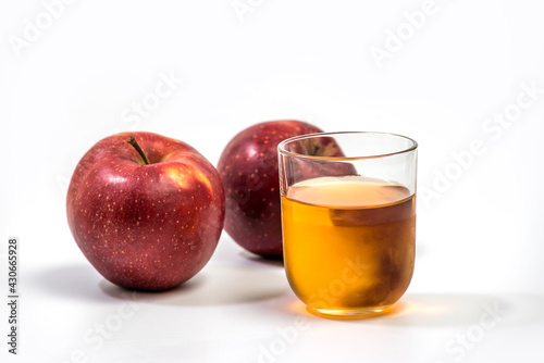 Close up of a glass of apple juice, with a whole and half apple. Natural apple juice on white background