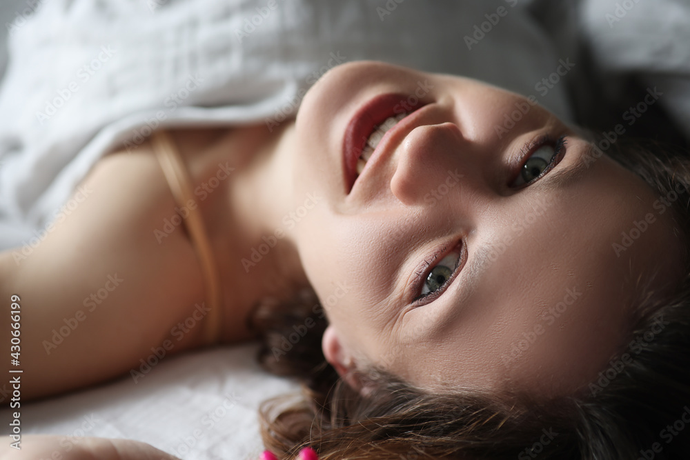 Young smiling woman lying in bed and looking up Young smiling woman lying in bed and looking up