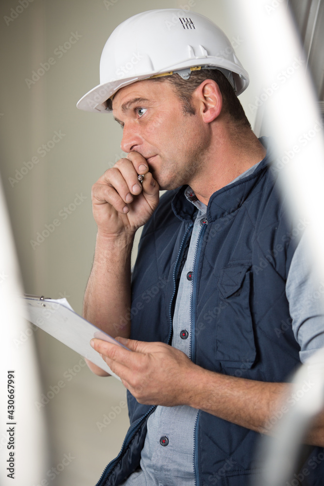 male builder with clipboard in deep contemplation male builder with clipboard in deep contemplation