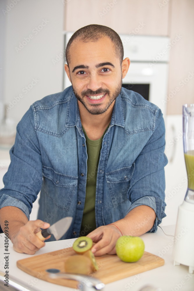 Fototapeta premium man cut kiwi fruits in slices on the table