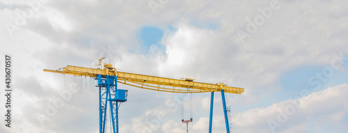 Overhead industrial construction crane on a background of blue sky with clouds photo