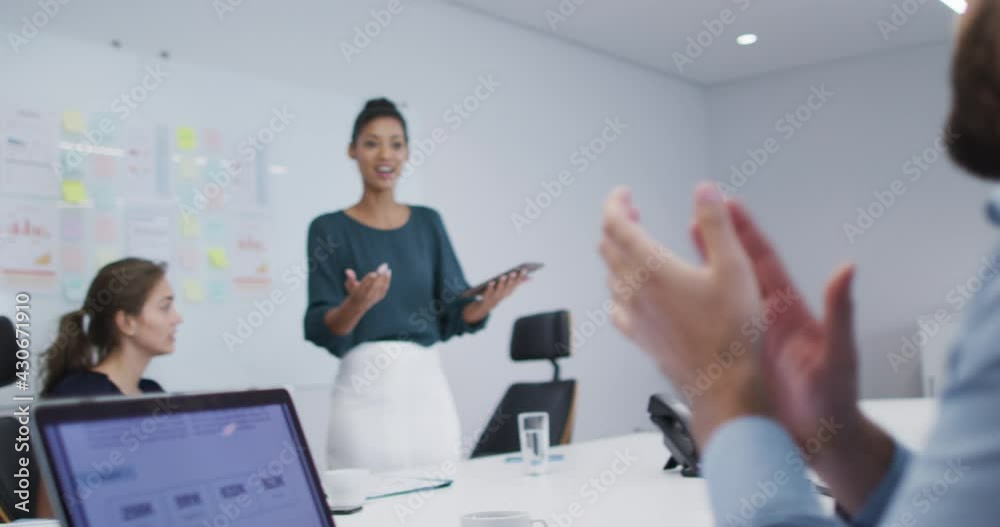 Diverse male and female office colleagues clapping after the presentation in meeting room at office