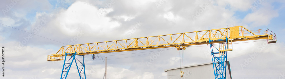 Industrial overhead hoisting construction crane on a background of blue sky with clouds