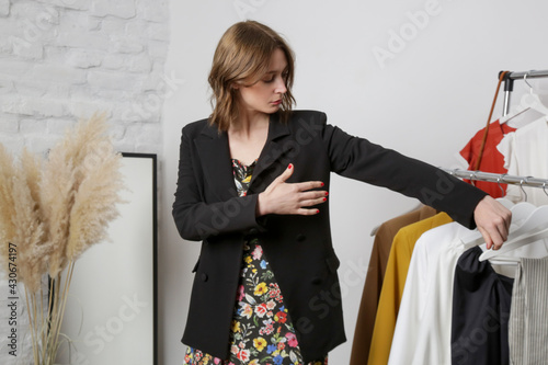 Canvas-taulu Young woman trying on black blazer in fashion atelier or personal wardrobe