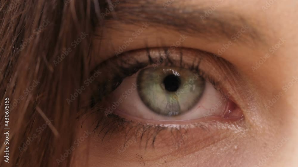 detail of woman's eye opens and stares at the camera - macro