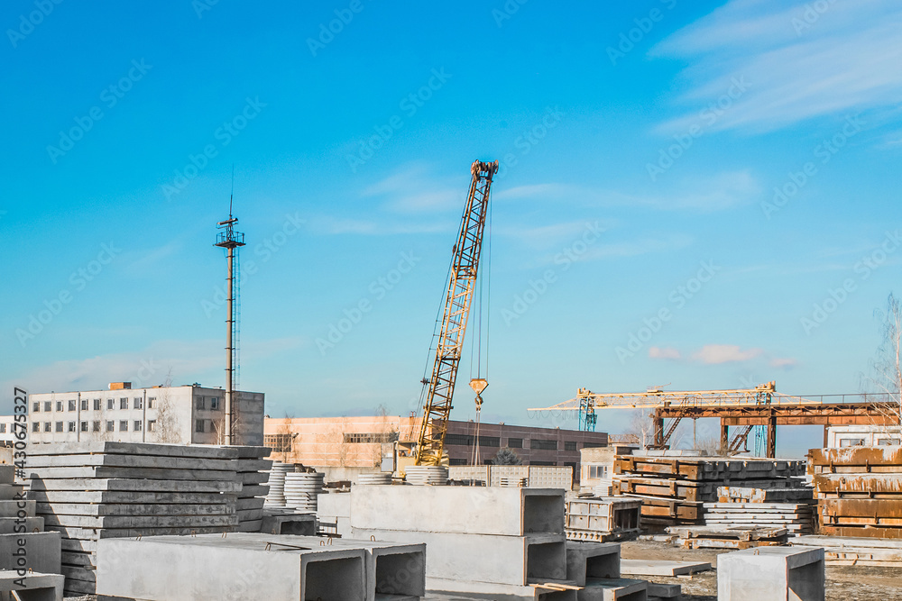 A machine crane at a construction site with a bunch of concrete structures. Concrete materials in an industrial urban area