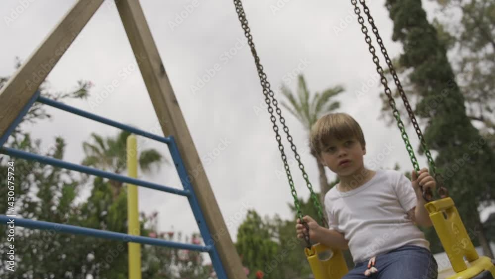 little boy swinging on a swing on the street
little boy swinging on a swing on the street