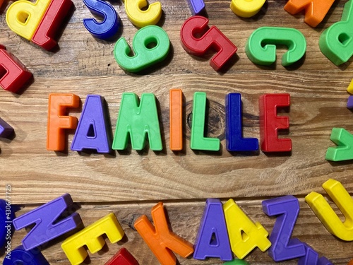 mot famille en français avec des lettres sur un fond bois