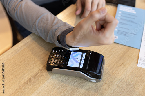 Unrecognizable man making wireless or contactless payment using smartwatch over nfc technology, apply to payment terminal. Concept e-commerce, people using contact less technology, business, cashless