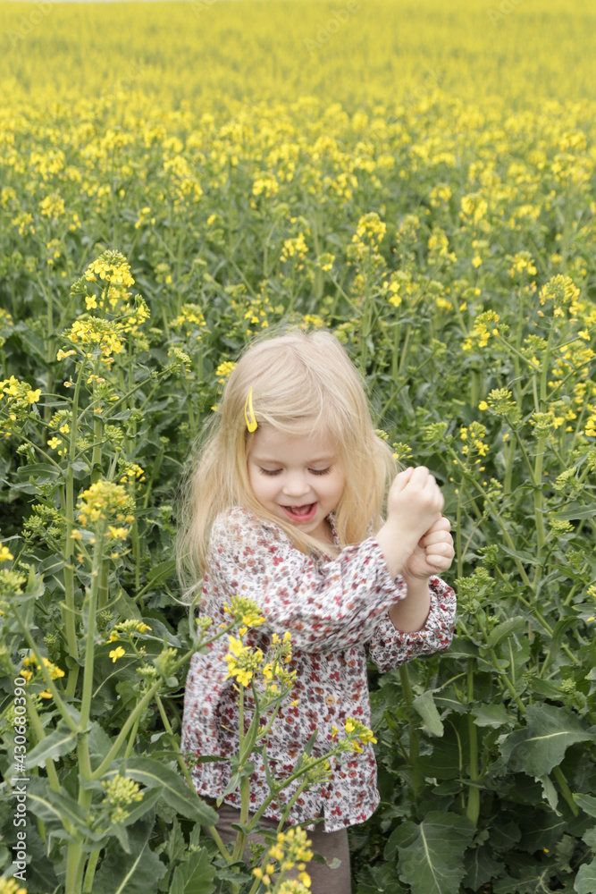 Outdoor candid portrait of cute blonde girl in field of yellow flowers. Outdoor candid portrait of cute blonde girl in field of yellow flowers.