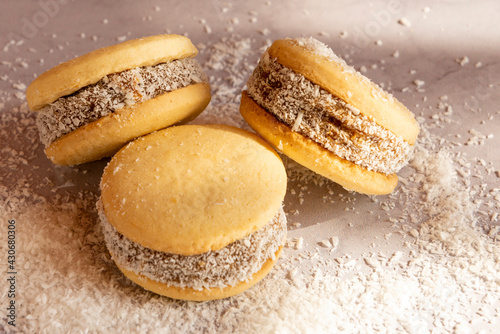 Fotografia Deliciosos alfajores de maicena rellenos de dulce de leche y espolvoreados con coco rallado, a luz de la mañana