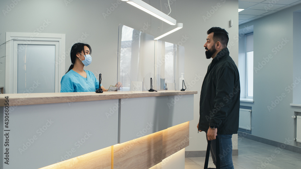 Fototapeta premium Bearded patient communicating with doctor and nurse on reception