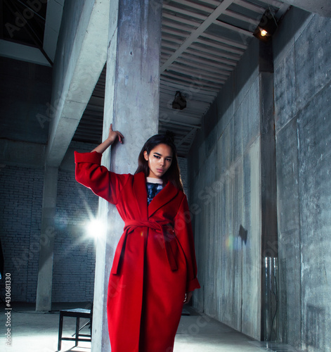 young pretty african american woman in luxury red coat posing fashionable on empty parking building, lifestyle rich people concept © iordani